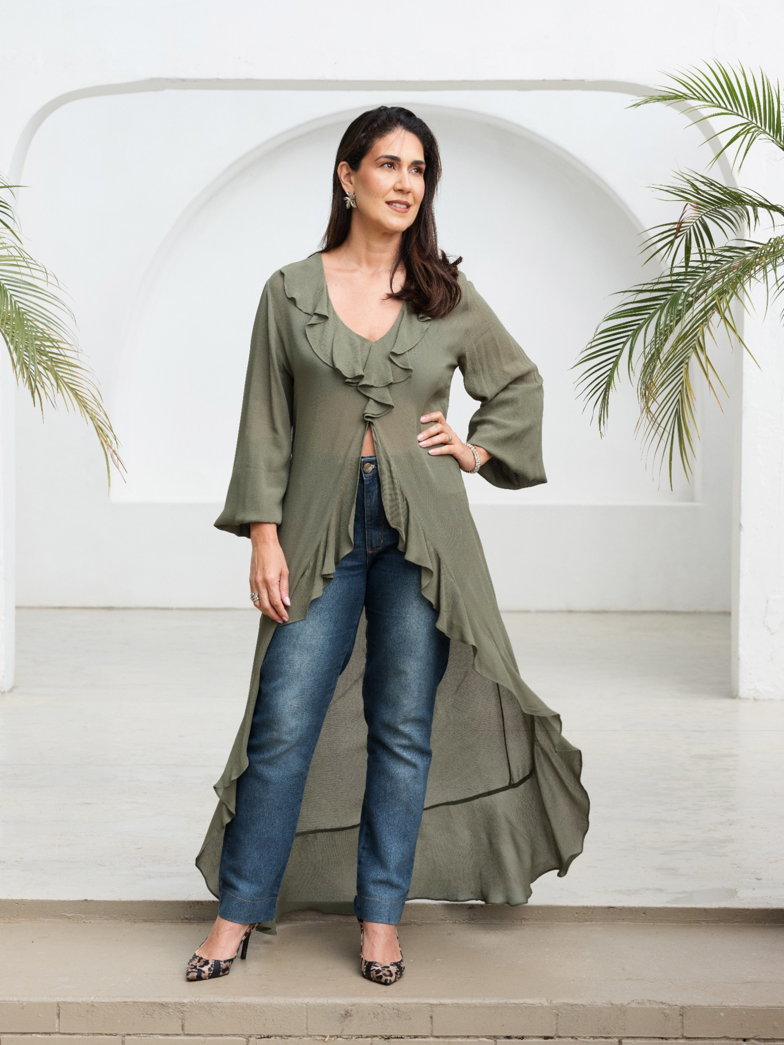 Cliente com look verde em movimento, em cenário de folhagens e luz natural